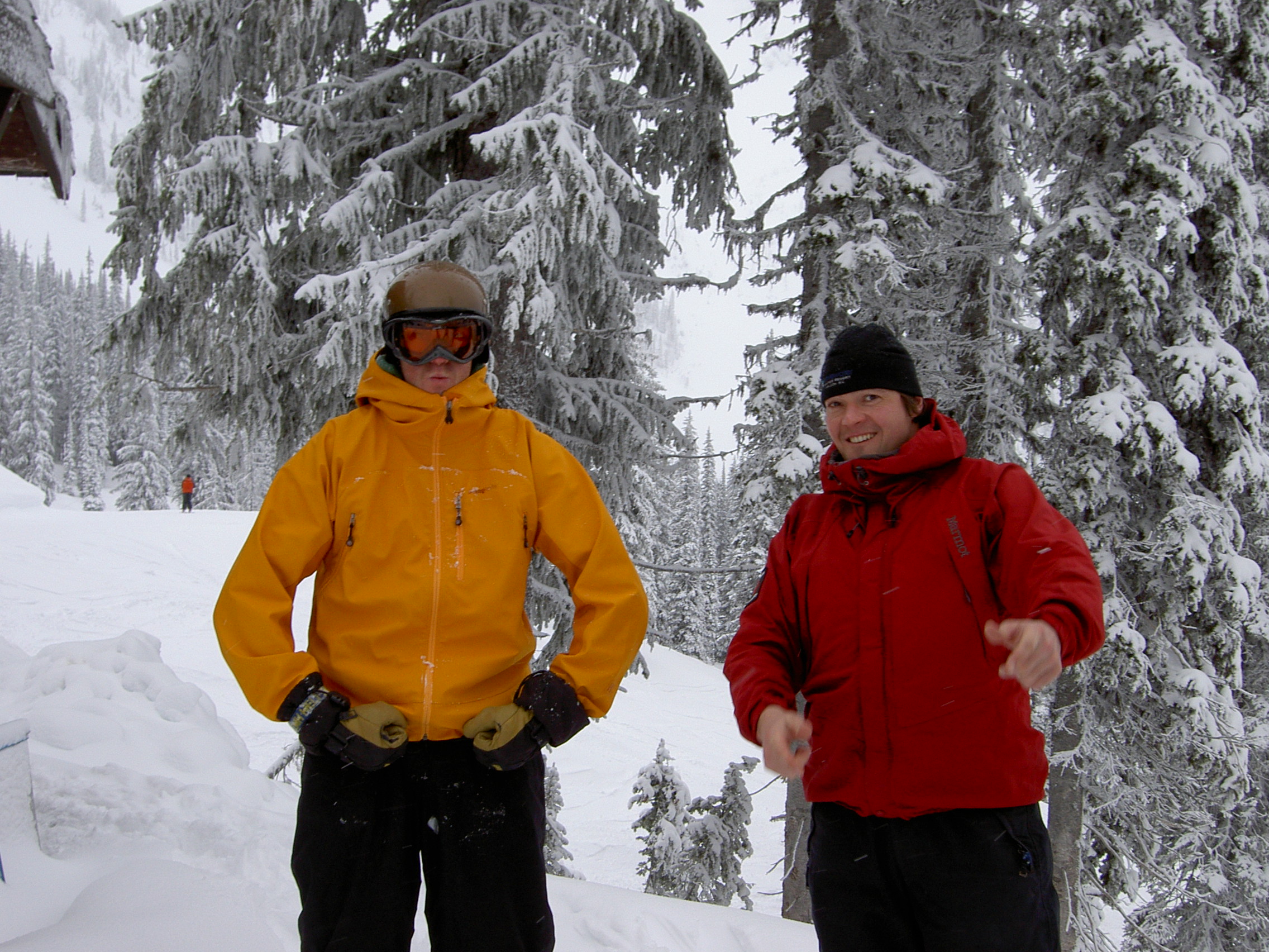 Two men standing in a snowy forest looking stoked.
